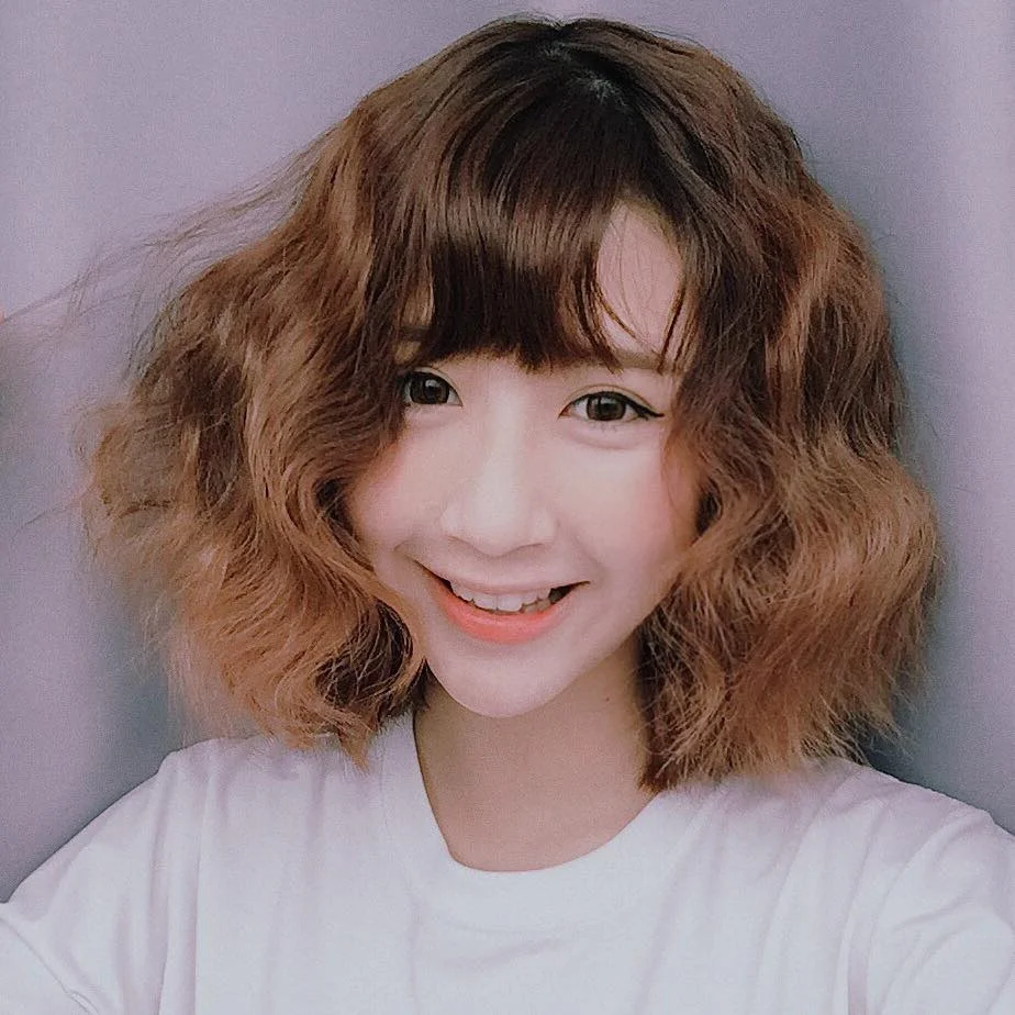 Cô gái cười tươi với mái tóc xoăn ngắn màu nâu